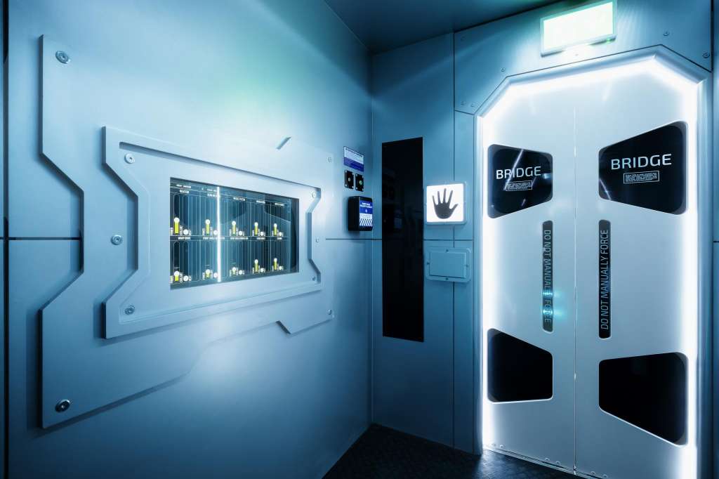 Modern corridor with illuminated display cases and vending machines featuring Bridge branding and neon lighting.