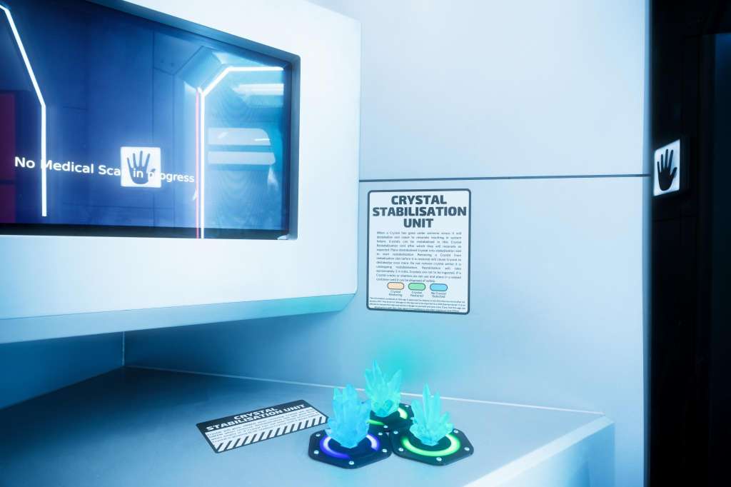 Interactive display with neon signage, informational placard, and illuminated crystal props on white counter.