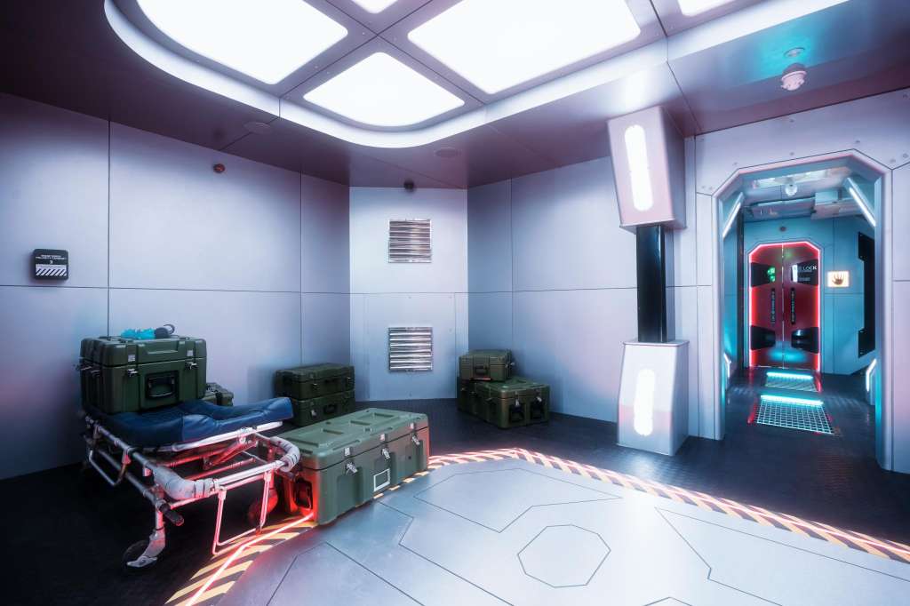 Modern interior with futuristic lighting, military-style crates, neon accents, and geometric floor patterns.