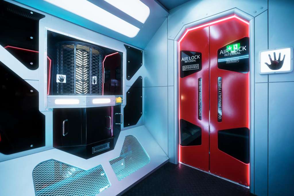 Modern interactive installation with neon-lit red and blue gaming pods featuring hand-recognition technology.