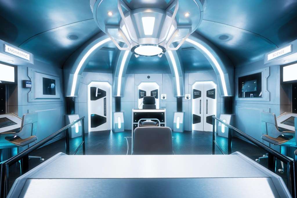 Futuristic bridge command center with blue lighting, control stations, and central captain's chair.