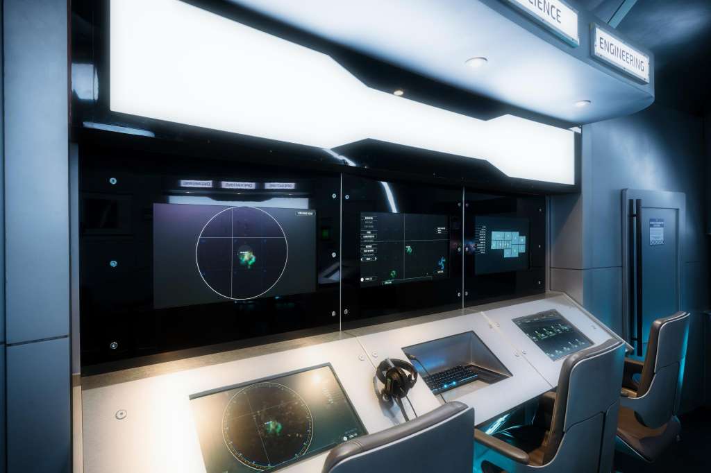 High-tech control room with multiple display screens showing radar and navigation data, workstations with monitors and headsets.