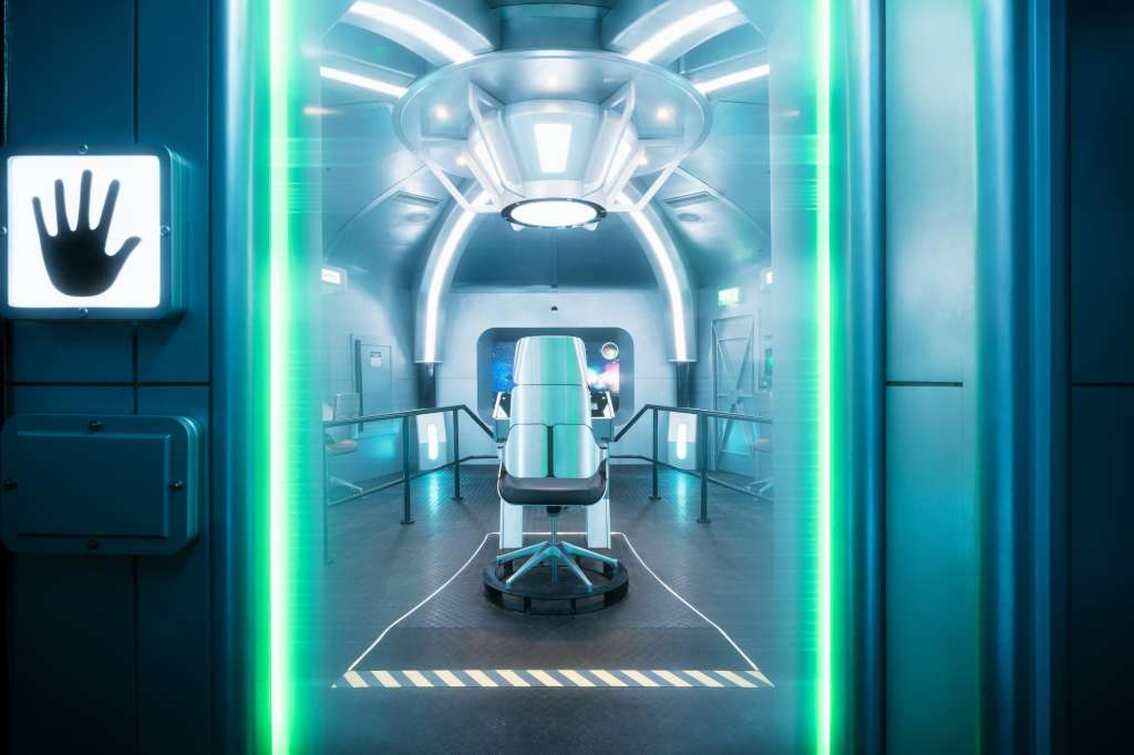 Futuristic corridor with neon green lighting, central pod structure, and symmetrical railings.
