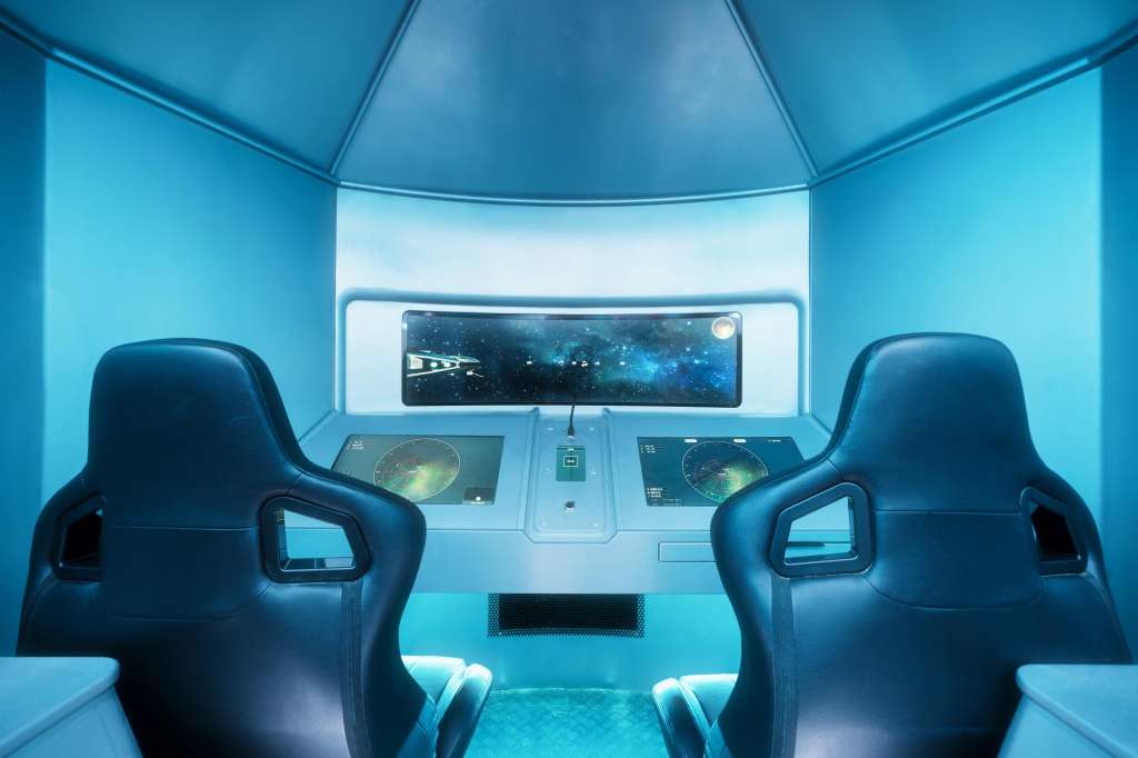 Futuristic spacecraft interior with two pilot seats, control panels, and starfield display screen.
