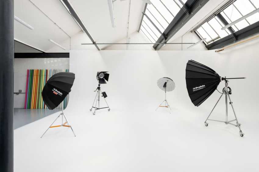 Photography studio with white walls, skylights, professional lighting rigs, and colorful backdrop panels.