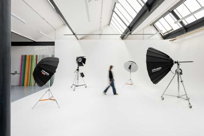 Photography studio with white walls, skylights, professional lighting rigs, and colorful backdrop panels.