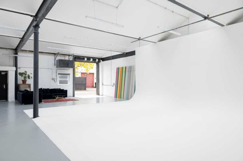 Industrial studio space with polished concrete floor, exposed beams, skylights, and open-plan layout with seating area.