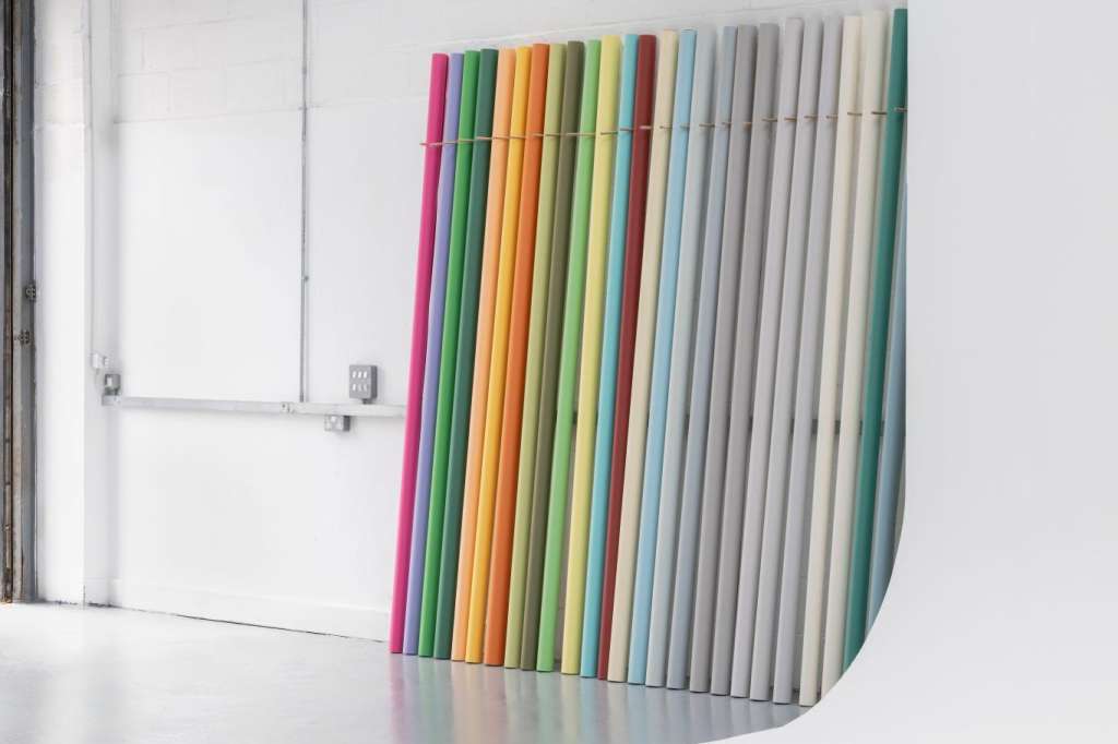 Modern gallery space with colorful vertical installation art against white walls and industrial ceiling.