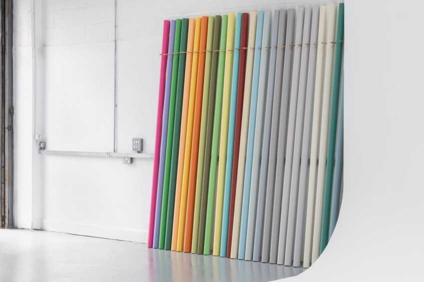 Modern gallery space with colorful vertical installation art against white walls and industrial ceiling.