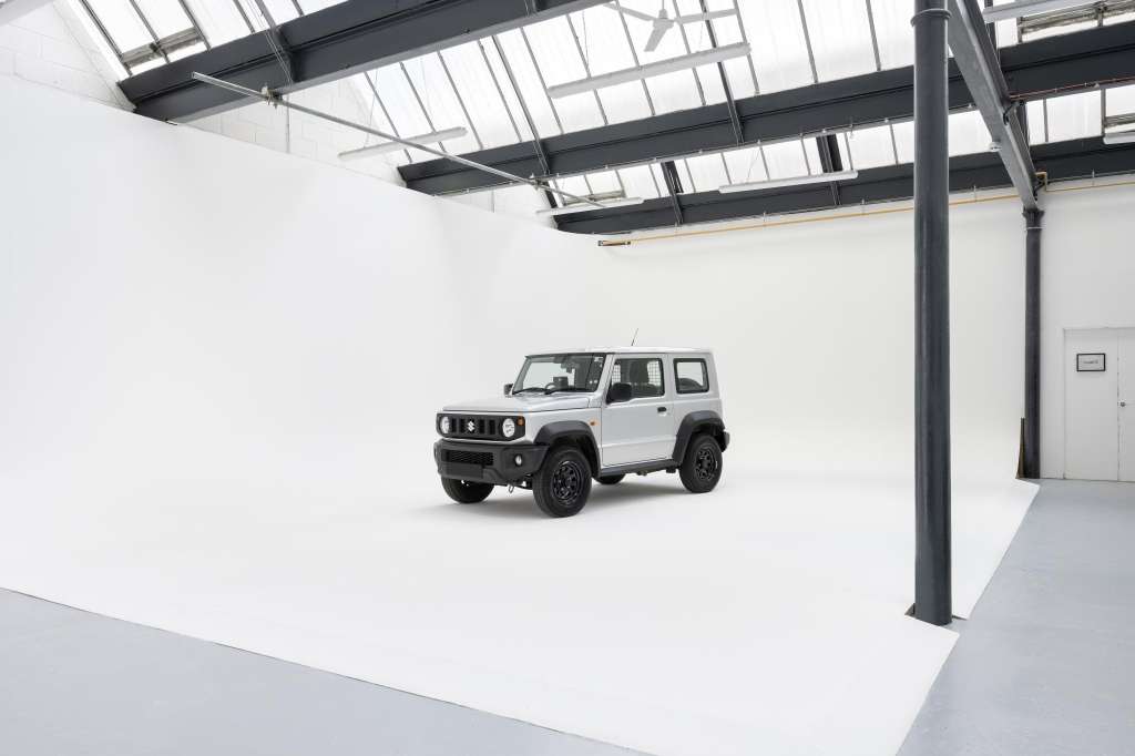 White SUV displayed in a bright industrial space with skylights, steel beams, and polished concrete flooring.