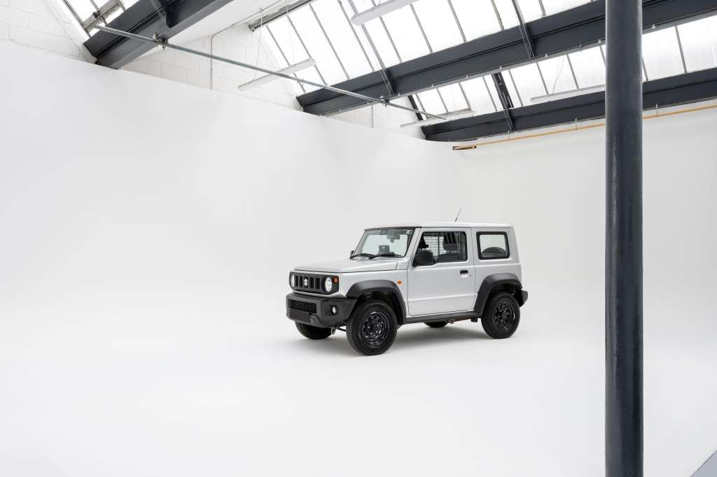 White SUV displayed in a bright industrial space with skylights and exposed steel beams.