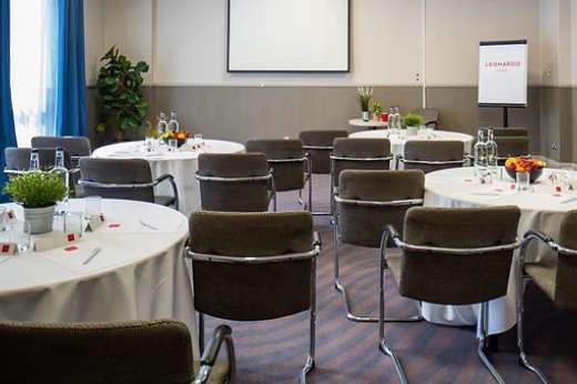 Rochdale room set with round tables, white linens, black chairs, and modern lighting for a formal event.