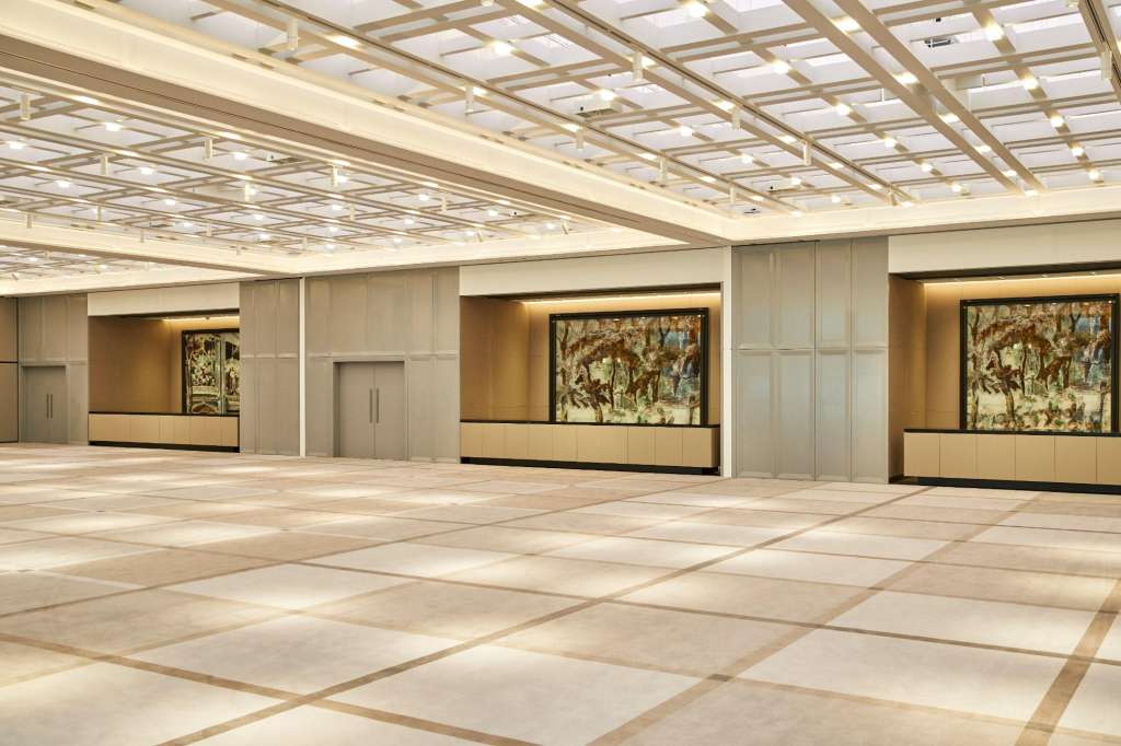 Ballroom with geometric ceiling grid, polished floor, neutral paneling, and framed artwork on walls.