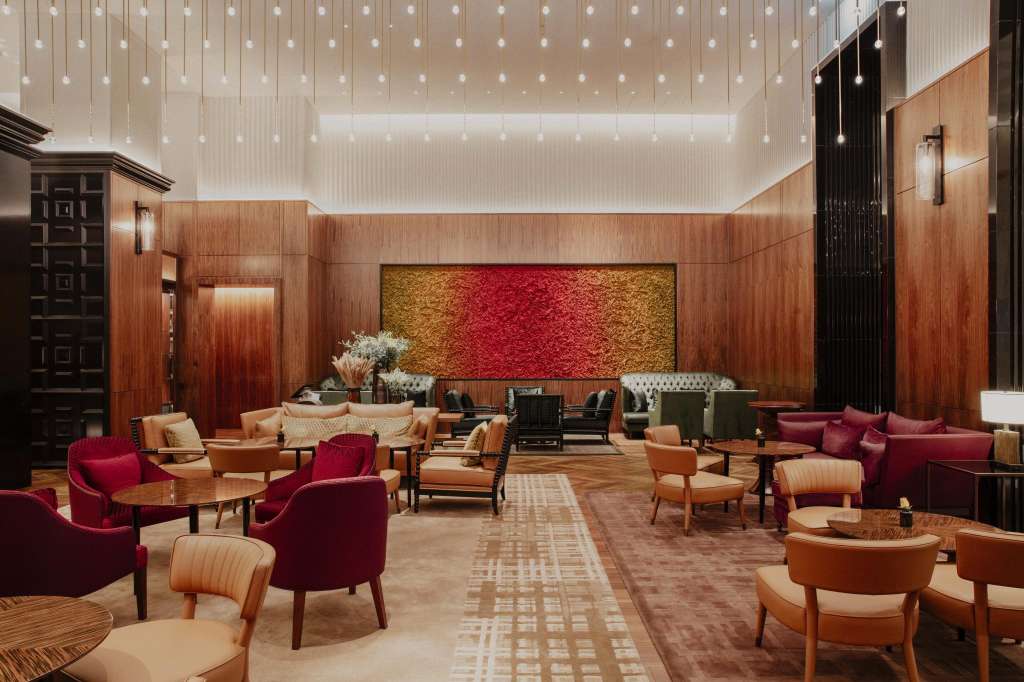 Ballroom with red and gold feature wall, hanging pendant lights, wood paneling, and scattered seating arrangements in red and tan.