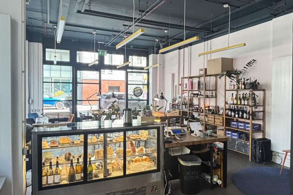 Modern retail or showroom space with illuminated display cases, shelving with products, and industrial ceiling fixtures.