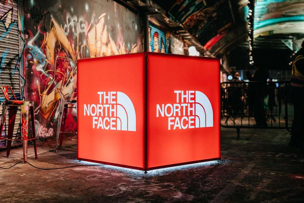 Industrial venue space with illuminated red branded cube display and colorful graffiti walls.