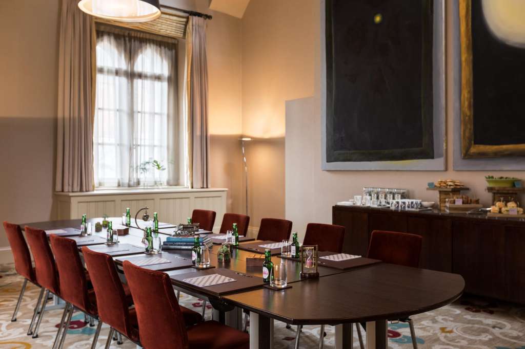The Gallery set up for a boardroom meeting with long table, burgundy chairs, water bottles, and natural light from tall windows.