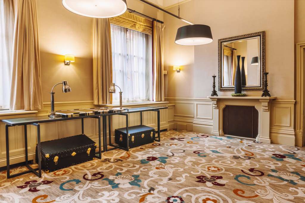 The Gallery with gold paneling, ornate fireplace, patterned carpet, and modern desk setup with pendant lighting.