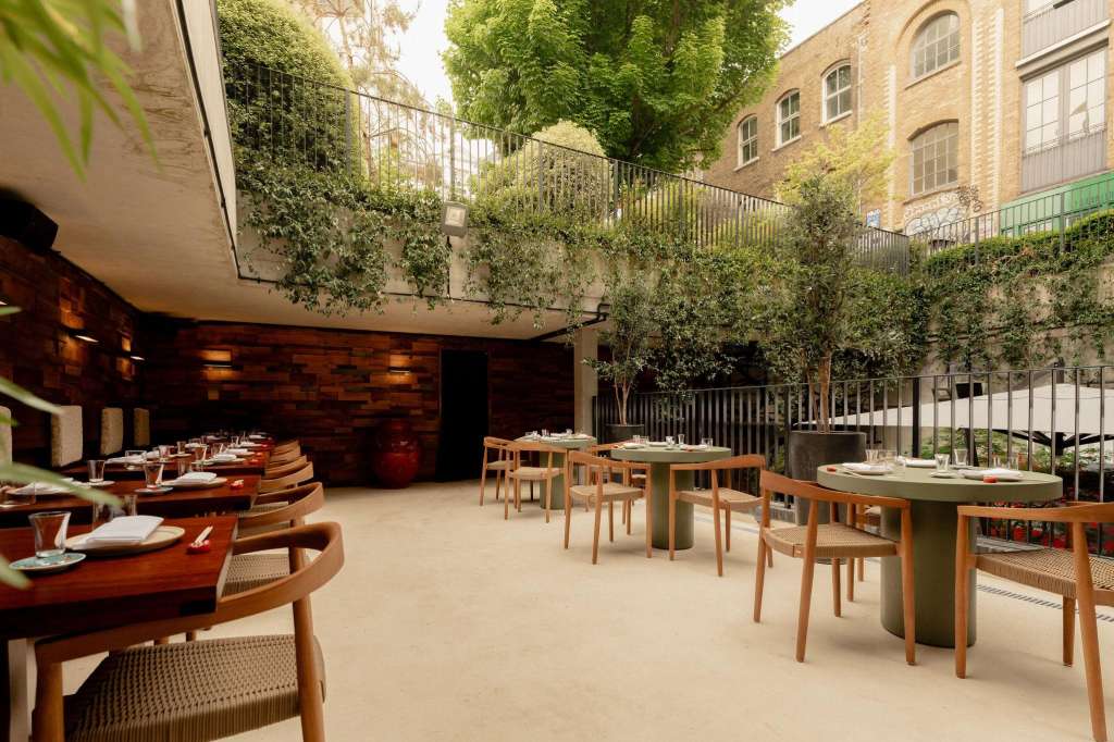 Mitsu Restaurant courtyard with wooden tables, chairs, ivy-covered walls, and natural daylight from above.