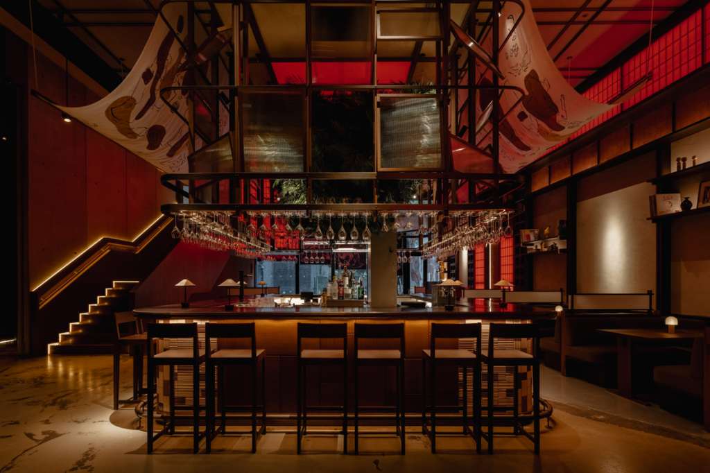 Mitsu Restaurant bar area with red walls, high ceilings, decorative banners, and bar seating.