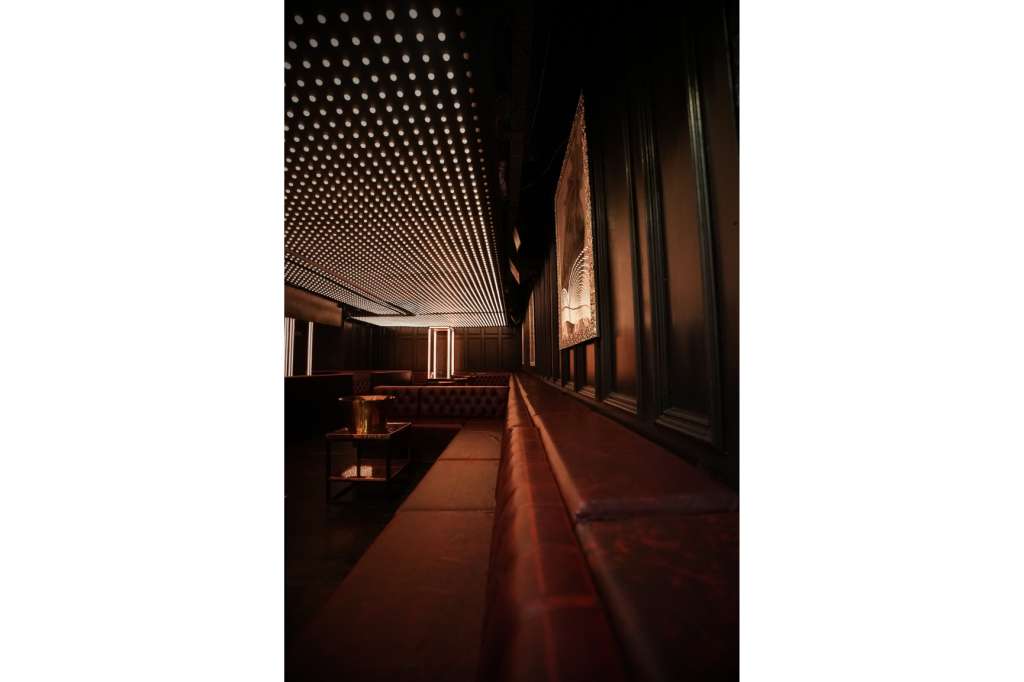 Modern corridor with geometric ceiling lights, dark wood paneling, and contemporary architectural design.