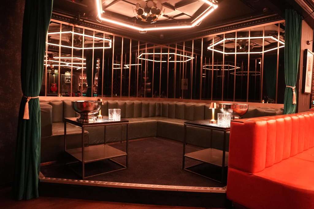 Modern lounge with neon lighting, banquette seating, and geometric decor in warm tones.