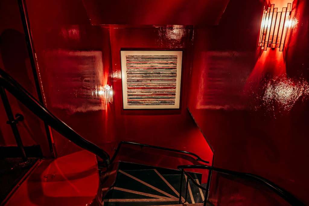 Stairwell with dramatic red lighting, illuminated wall art, and geometric light fixtures.