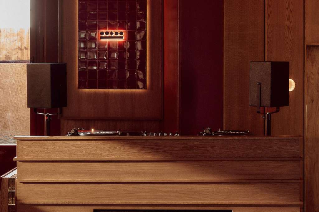 The Club bar counter with wood paneling, neon signage, speakers, and deep red walls.