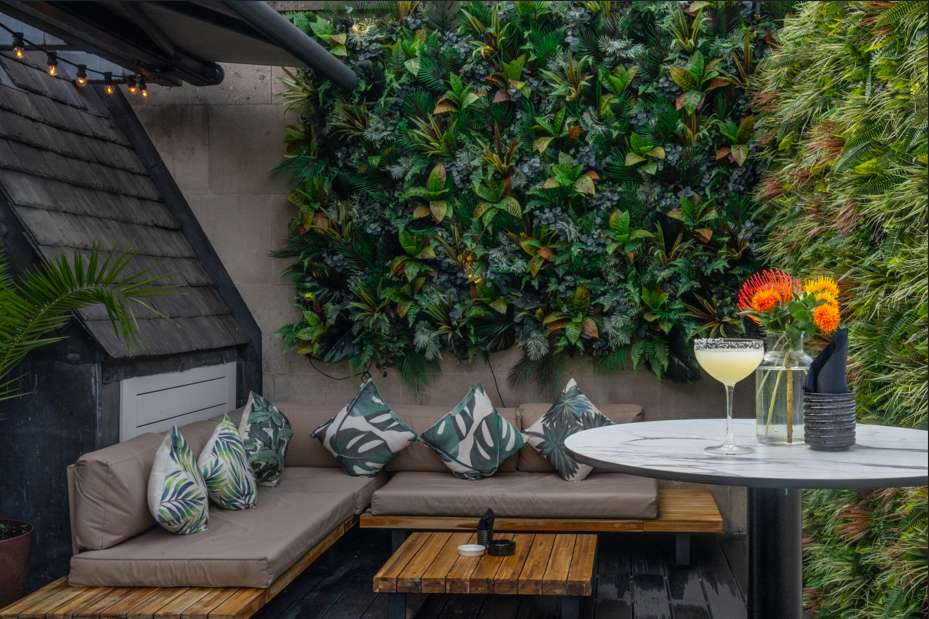 Outdoor terrace with built-in seating, cocktail table, living plant wall, and tropical flowers.