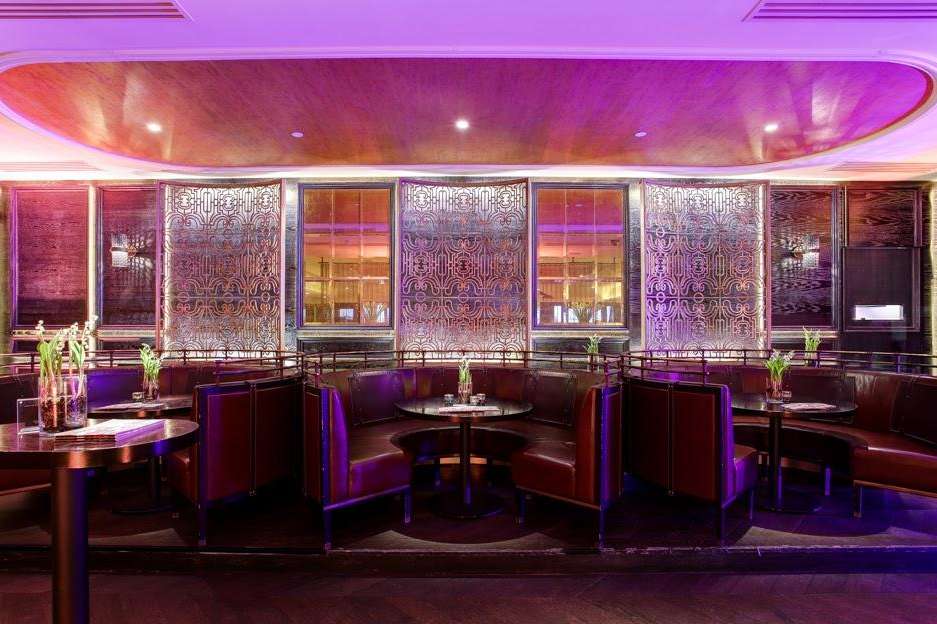 El Salon with burgundy banquette seating, round tables, ornate screens, and purple ambient lighting.