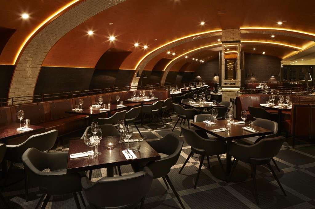 El Salon dining room with arched ceiling, ambient lighting, round tables set with glassware and place settings.