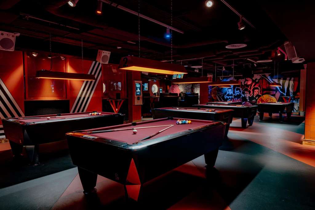 Duck pin bowling alley with multiple tables, red and black lighting, and entertainment setup.