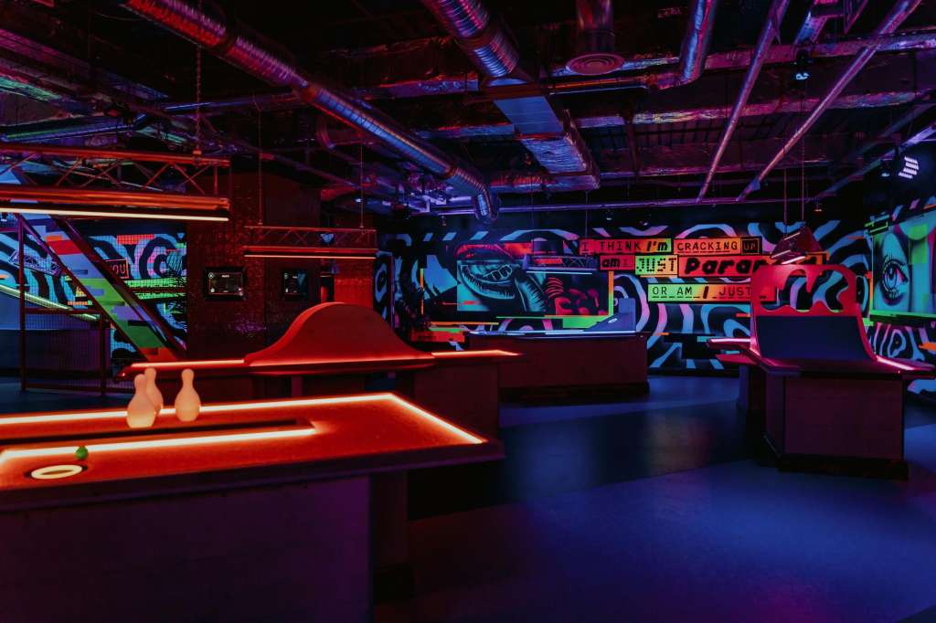 VIP Room with neon-lit bar counters, vibrant street art murals, and colorful overhead lighting in dark interior.