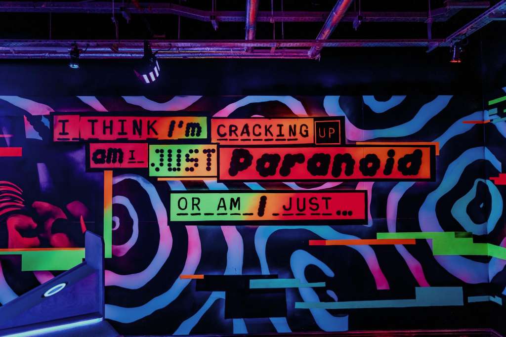 VIP Room with vibrant neon signage and colorful geometric wall art under stage lighting.
