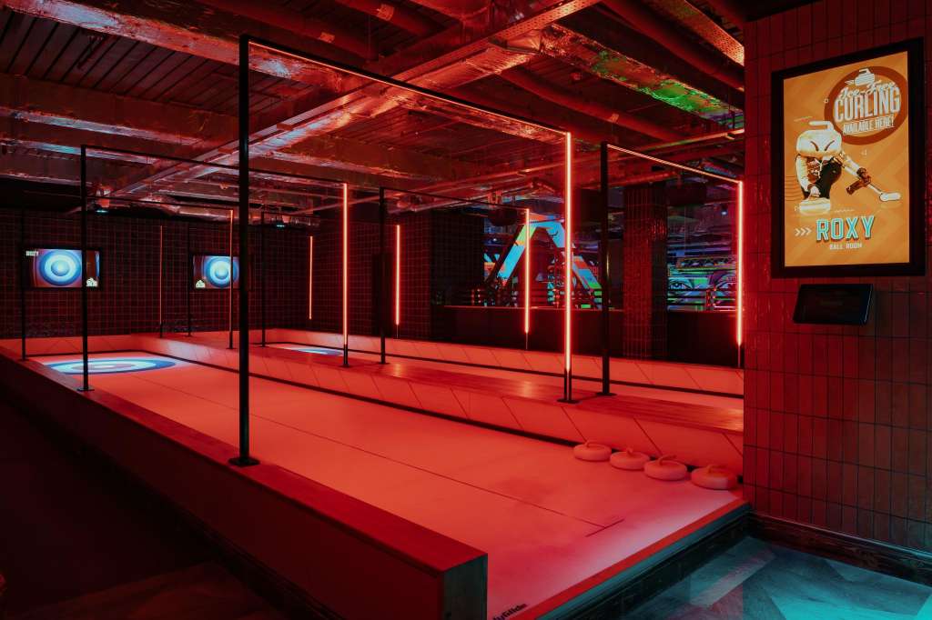Crazy Pool room with red neon lighting, curling targets on floor, and glass partitions dividing the space.