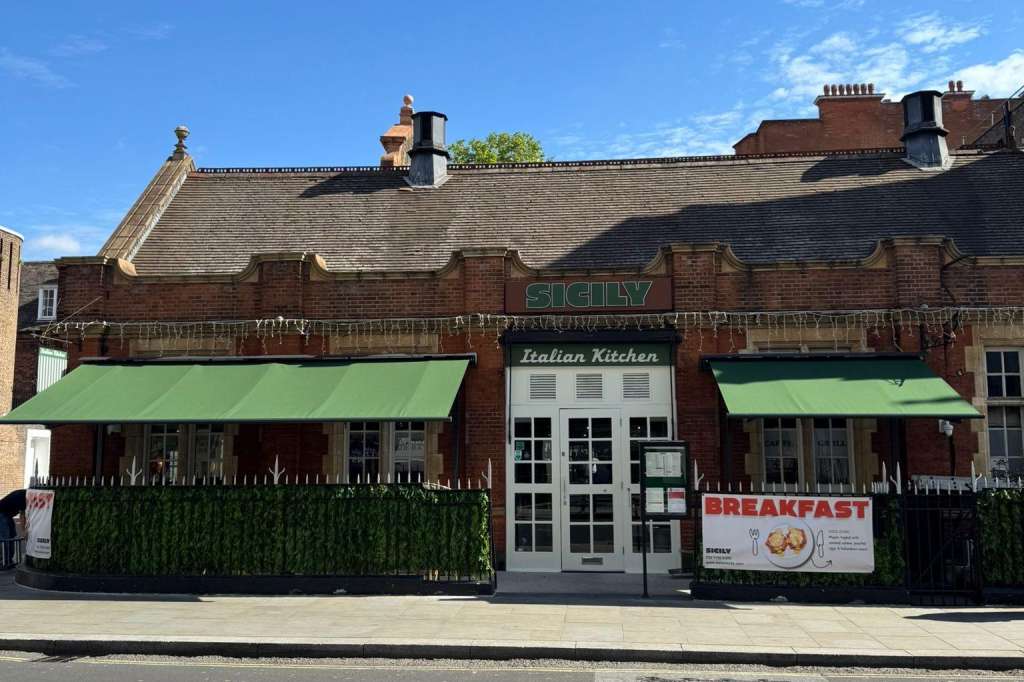 Exterior of brick restaurant building with green awnings, signage reading Italian Kitchen and Breakfast.