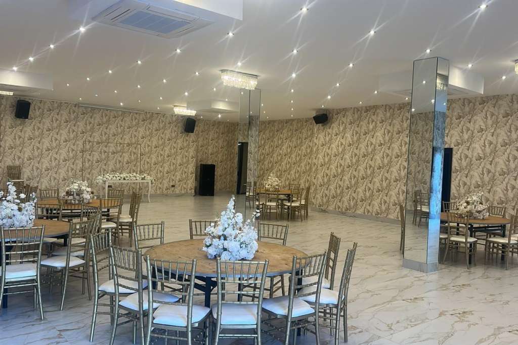 Ballroom set with round tables, chiavari chairs, white floral centerpieces, and recessed ceiling lighting.
