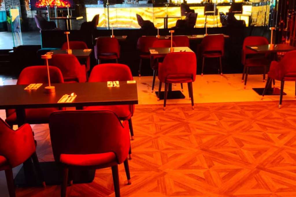 Modern lounge space with red chairs, low tables, and warm ambient lighting throughout the room.