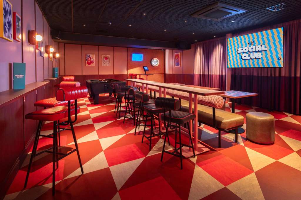 Trophy Room with red and cream diamond floor, high-top tables, bar seating, and branded screen display.
