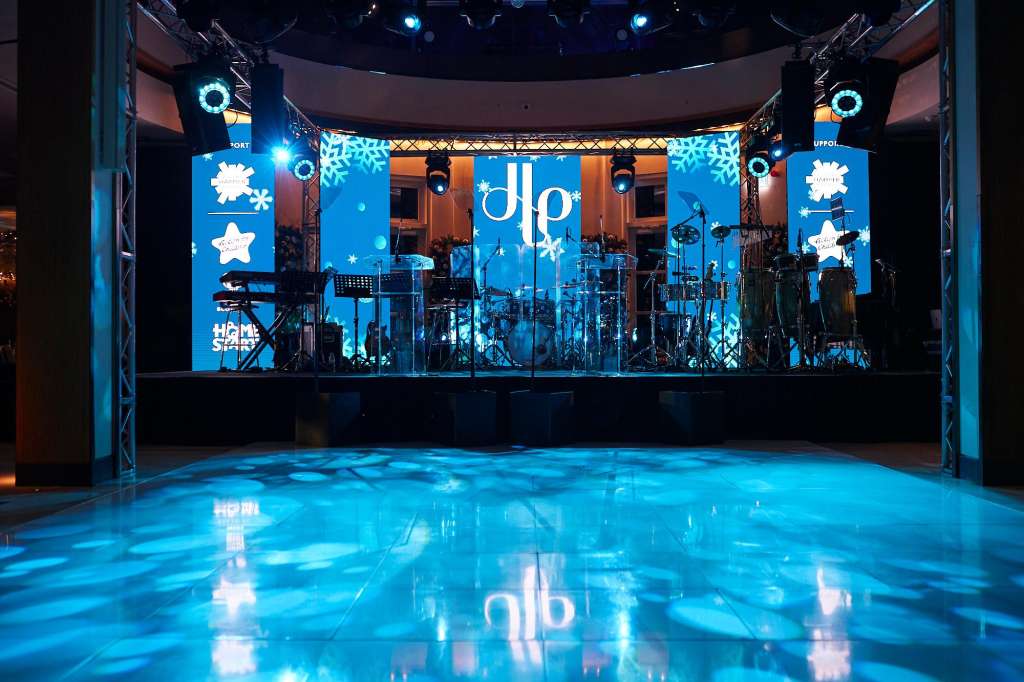 Palm Court set up for product launch with stage, blue lighting, snowflake projections, and band equipment.