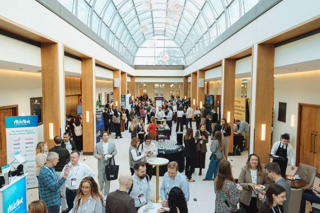 Palm Court with glass roof, wooden columns, and standing guests mingling with drinks and catering stations.