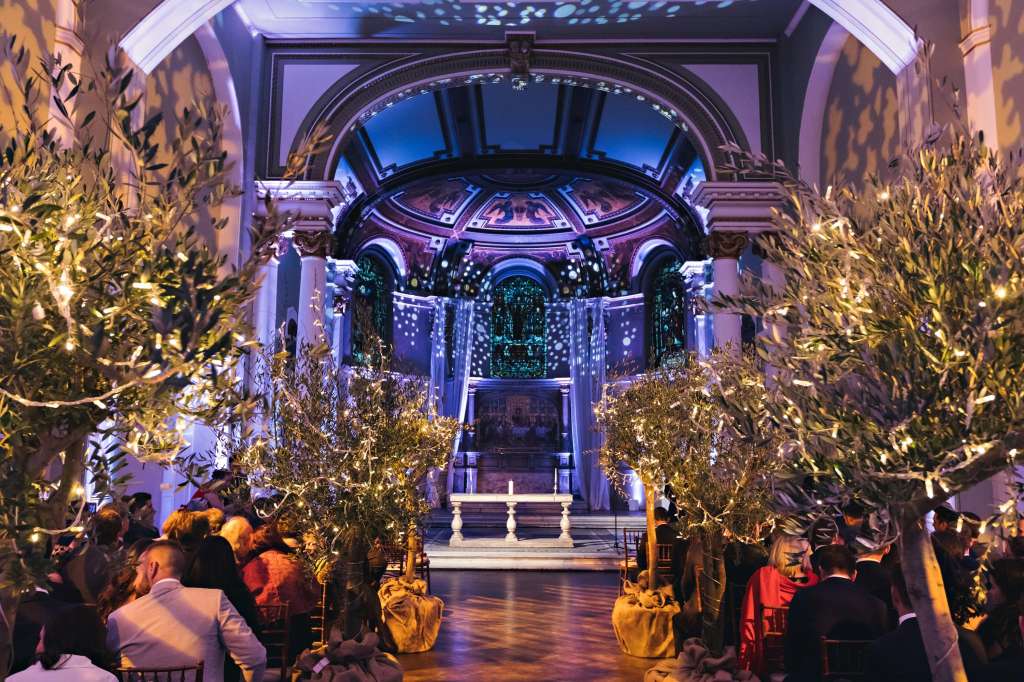 The Galleries set for an evening reception with illuminated foliage, dramatic blue and purple lighting, and architectural archways.