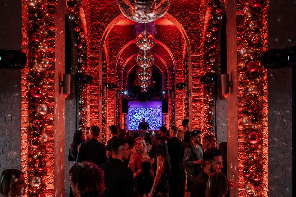 The Galleries set up for an evening event with red ambient lighting, disco ball, and decorated archways lined with festive ornaments.