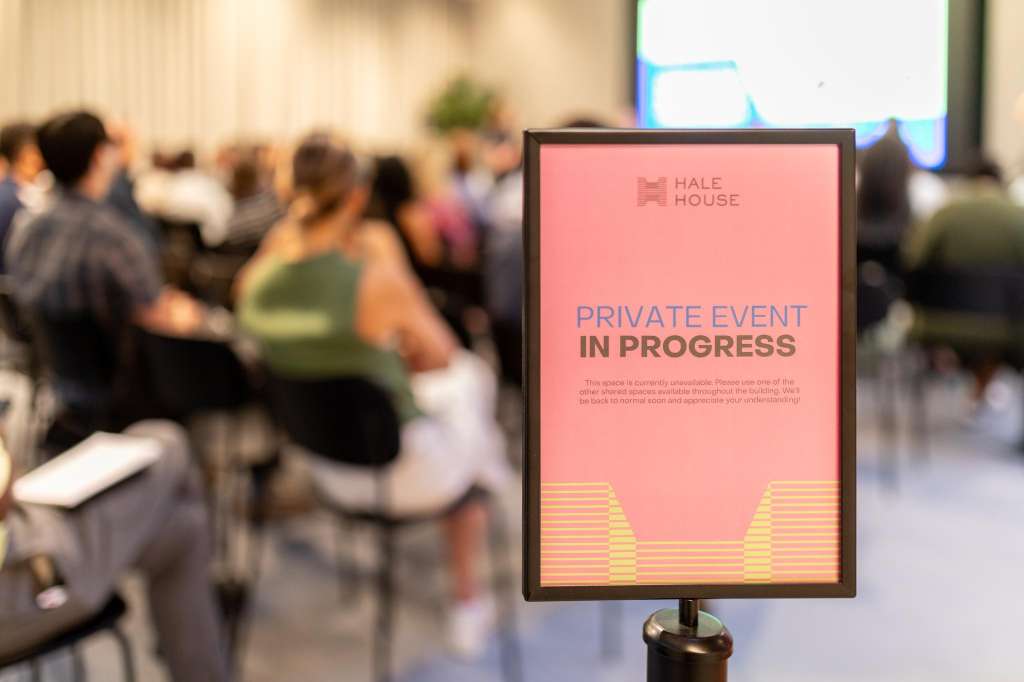 Cormack room with seated attendees, presentation screen visible, and Hale House event signage in foreground.
