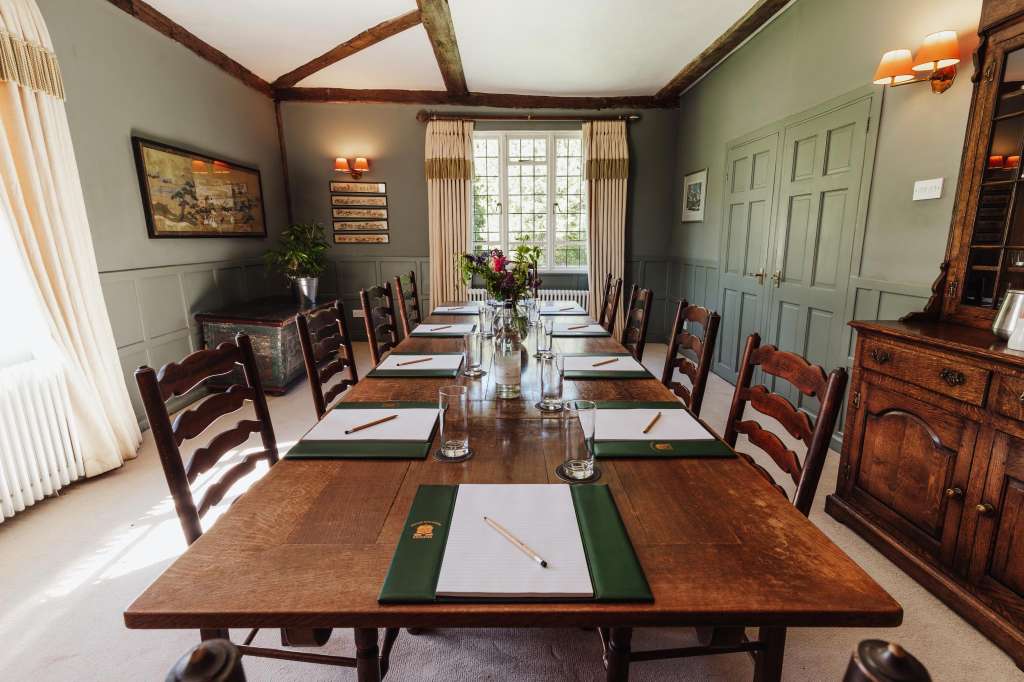 Grainstore dining room set for a formal meal with long wooden table, place settings, and exposed beam ceiling.
