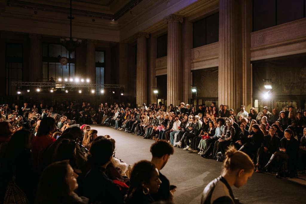 Main Hall set up for a fashion show or product launch with runway, stage lighting, and seated audience lining both sides.