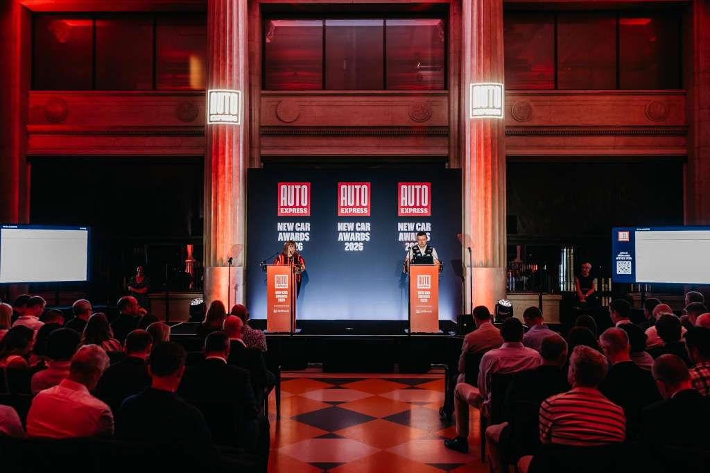 Main Hall set up for a product launch with stage, podiums, large screens, and seated audience under red lighting.