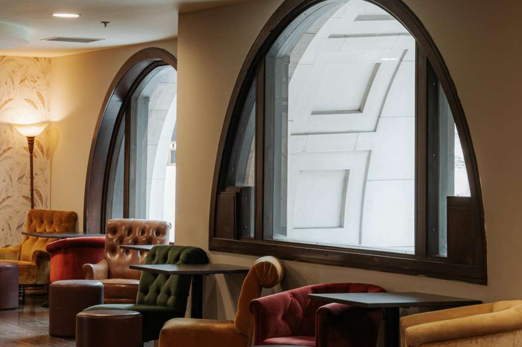 Main Hall lounge area with leather seating, large arched windows, warm lighting, and contemporary furnishings.