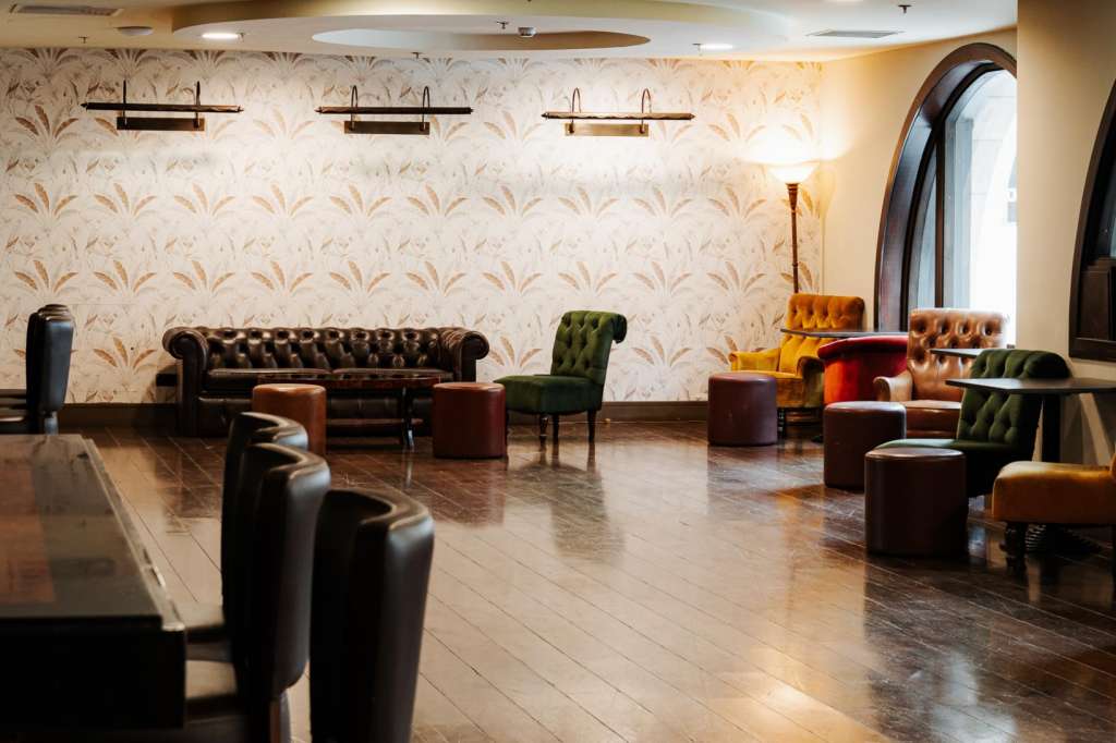 Main Hall with lounge seating, chesterfield sofas, accent chairs, patterned wallpaper, and recessed lighting.