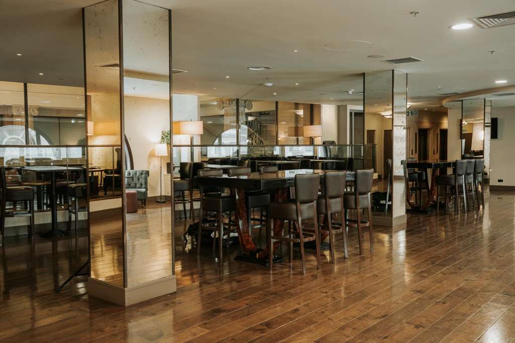 Main Hall with high ceilings, glass partitions, bar seating, and warm ambient lighting throughout.